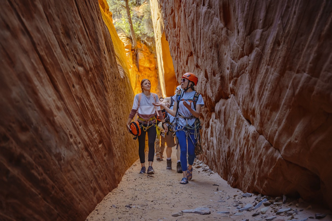 A guide leading travelers through a red rock slot canyon
